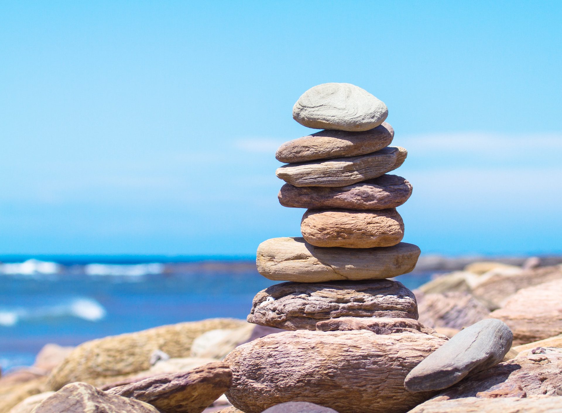 a pile of rocks with water in the background and a blue sky