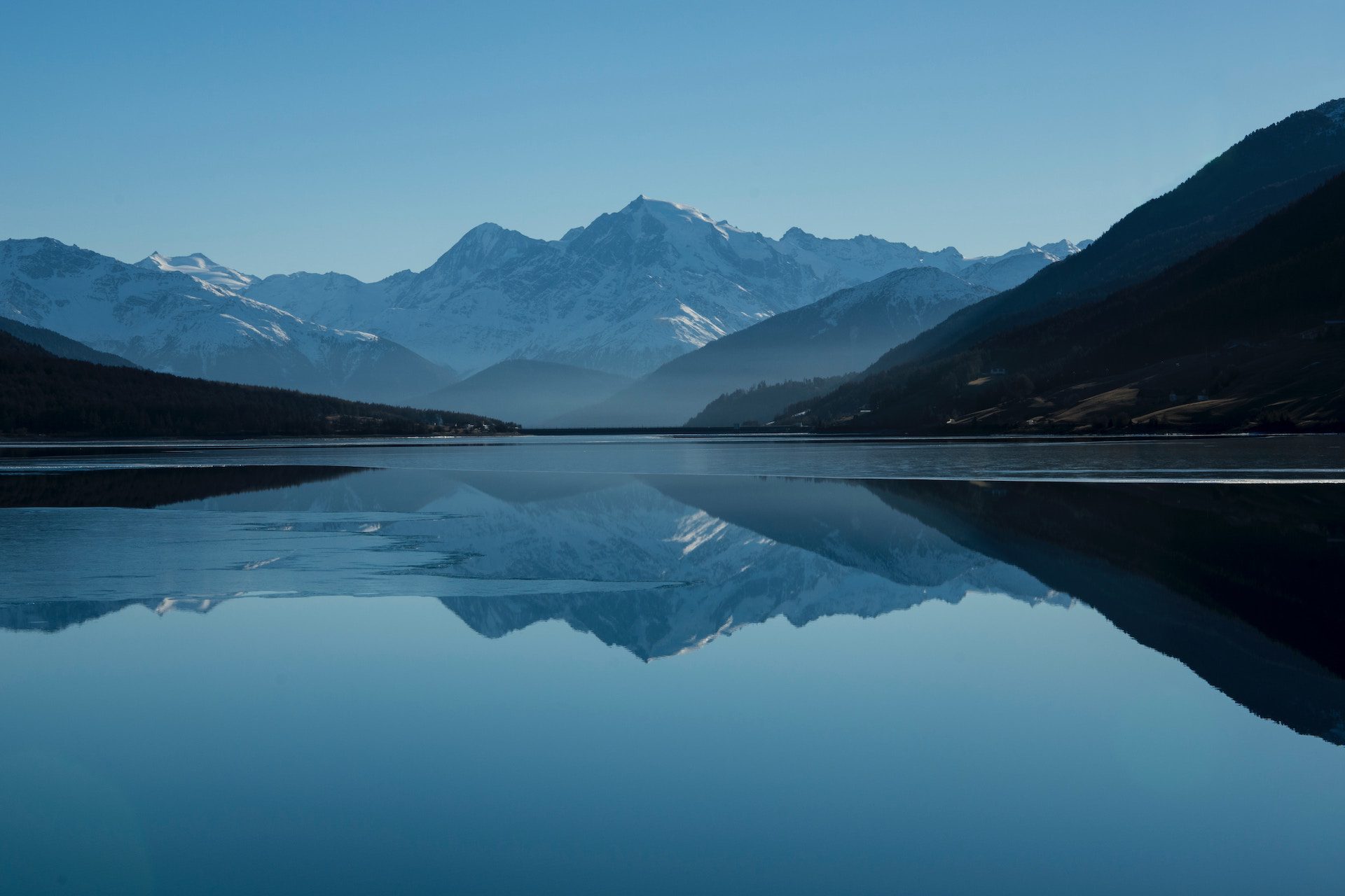 body of water with mountains in the background and mountains reflected in the water