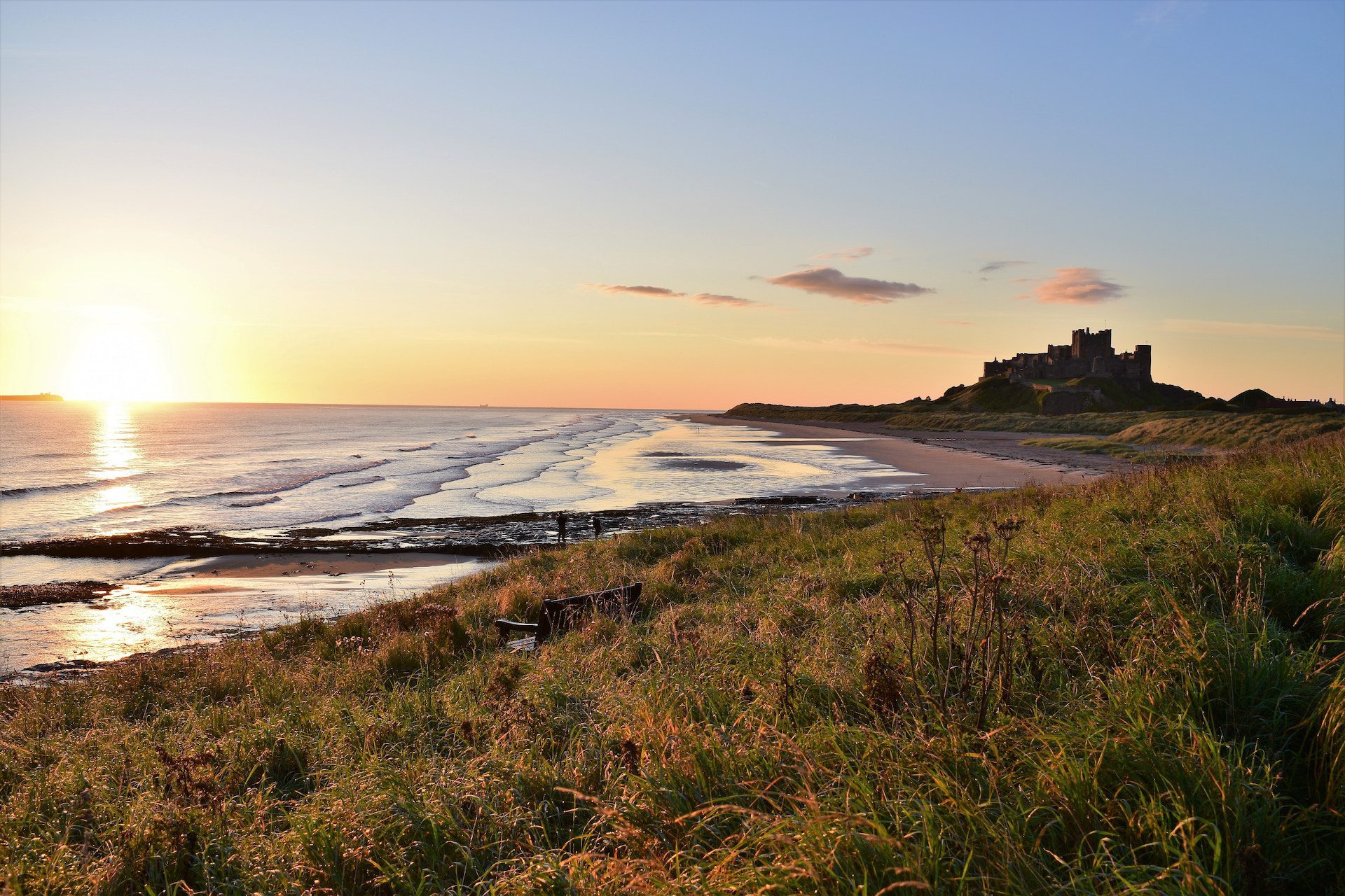 coastal town with castle in the background and sea and grass in the foreground
