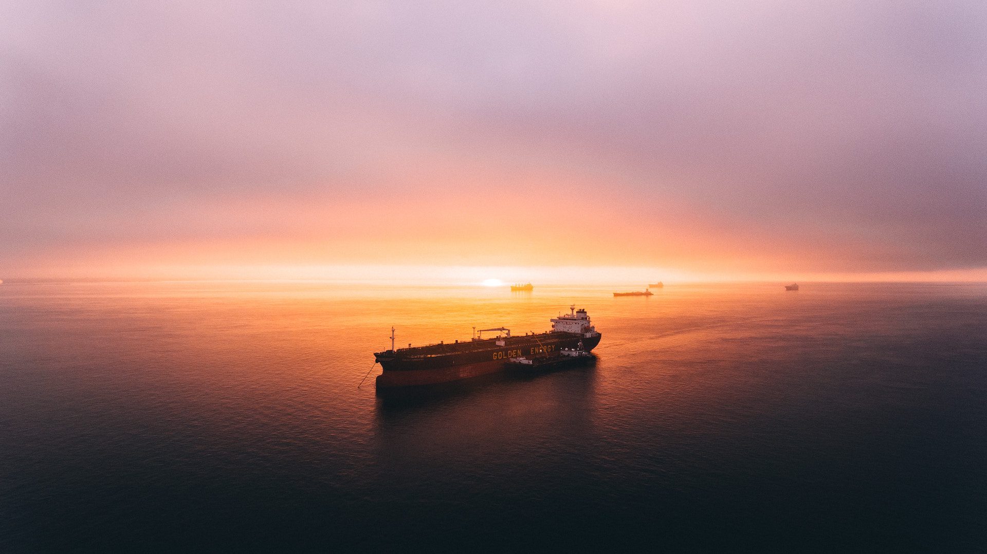 shipping container moving across water with sunset backdrop
