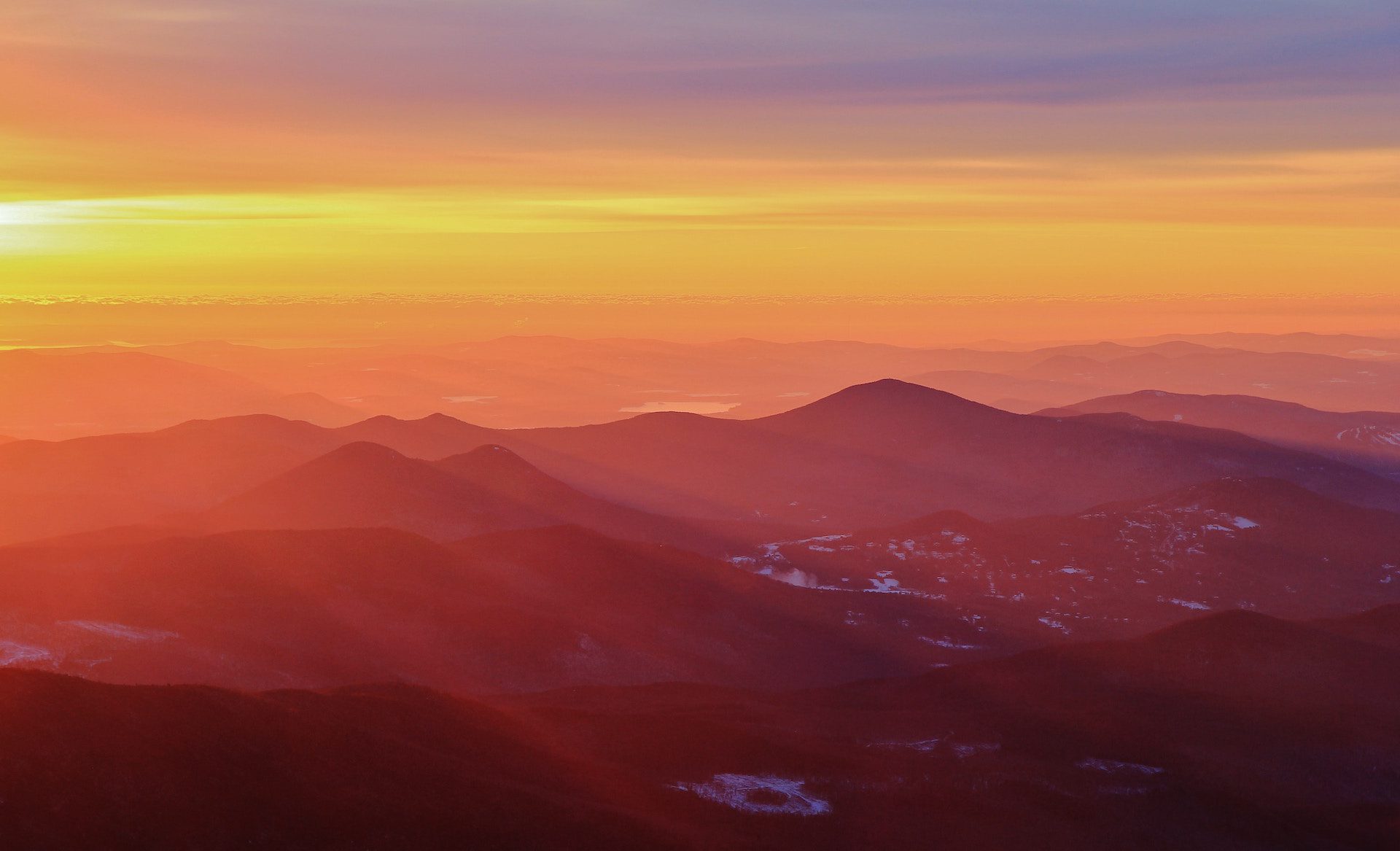 view of hills and mountains with buildings in the distance and a sunset background