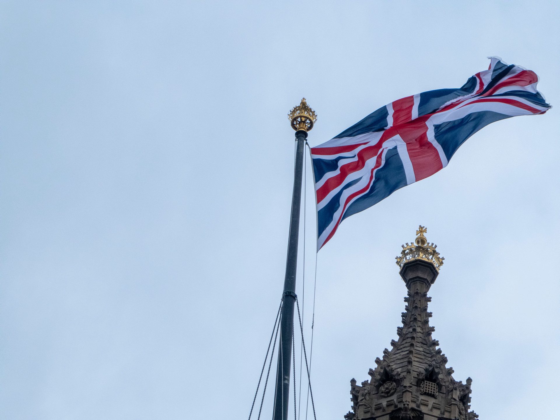 close up of a flag of England against a blue sky and building in the background
