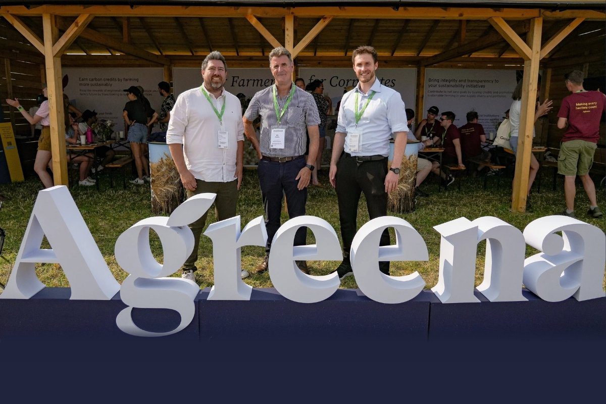 Three people standing in front of large Agreena sign at an outdoor event