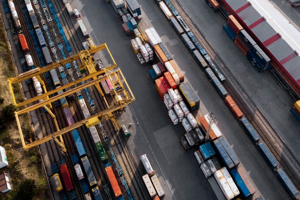 Aerial view of a busy train yard with numerous freight trains, cargo containers, and gantry cranes