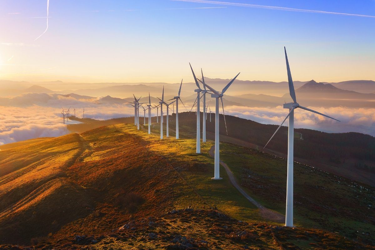 Wind turbines generating renewable energy on a hillside at sunrise